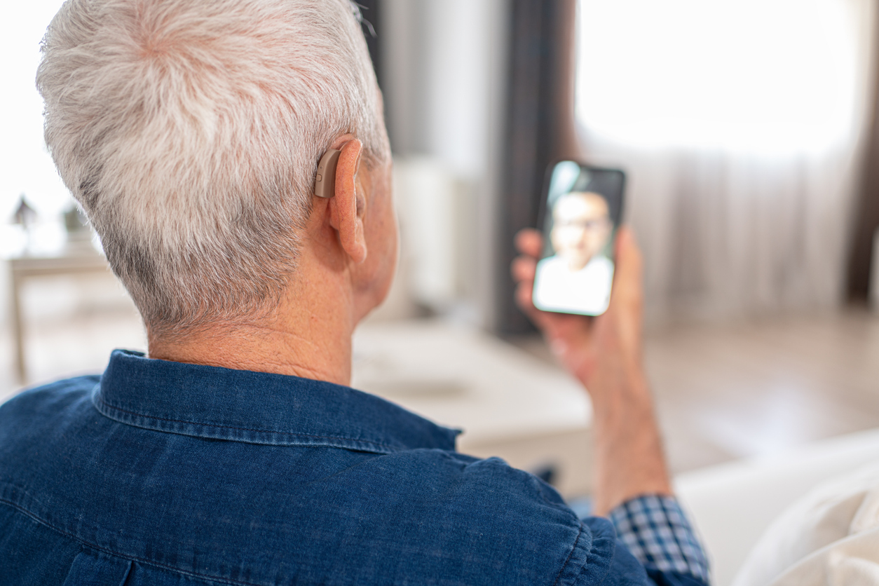 Man with hearing aids on a video call, using Bluetooth to stream the sound to his hearing aids.