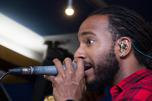 Professional musician singing into a microphone, wearing custom musician's earplugs for hearing protection.