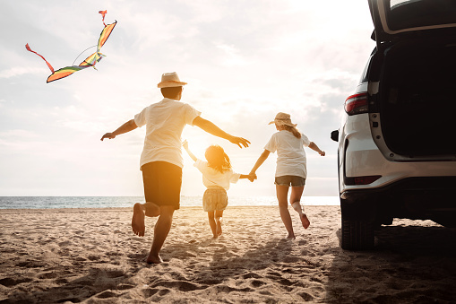Family jumps out of the car and races to the beach on a beautiful evening.
