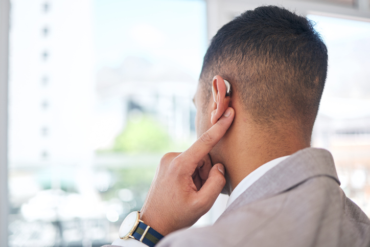 Man with hearing aids touches his ear